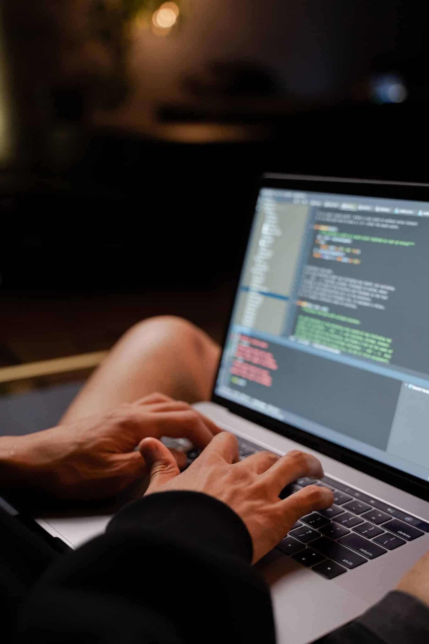 Close-up of hands coding on a laptop with a dark theme editor, representing open-source AI model development