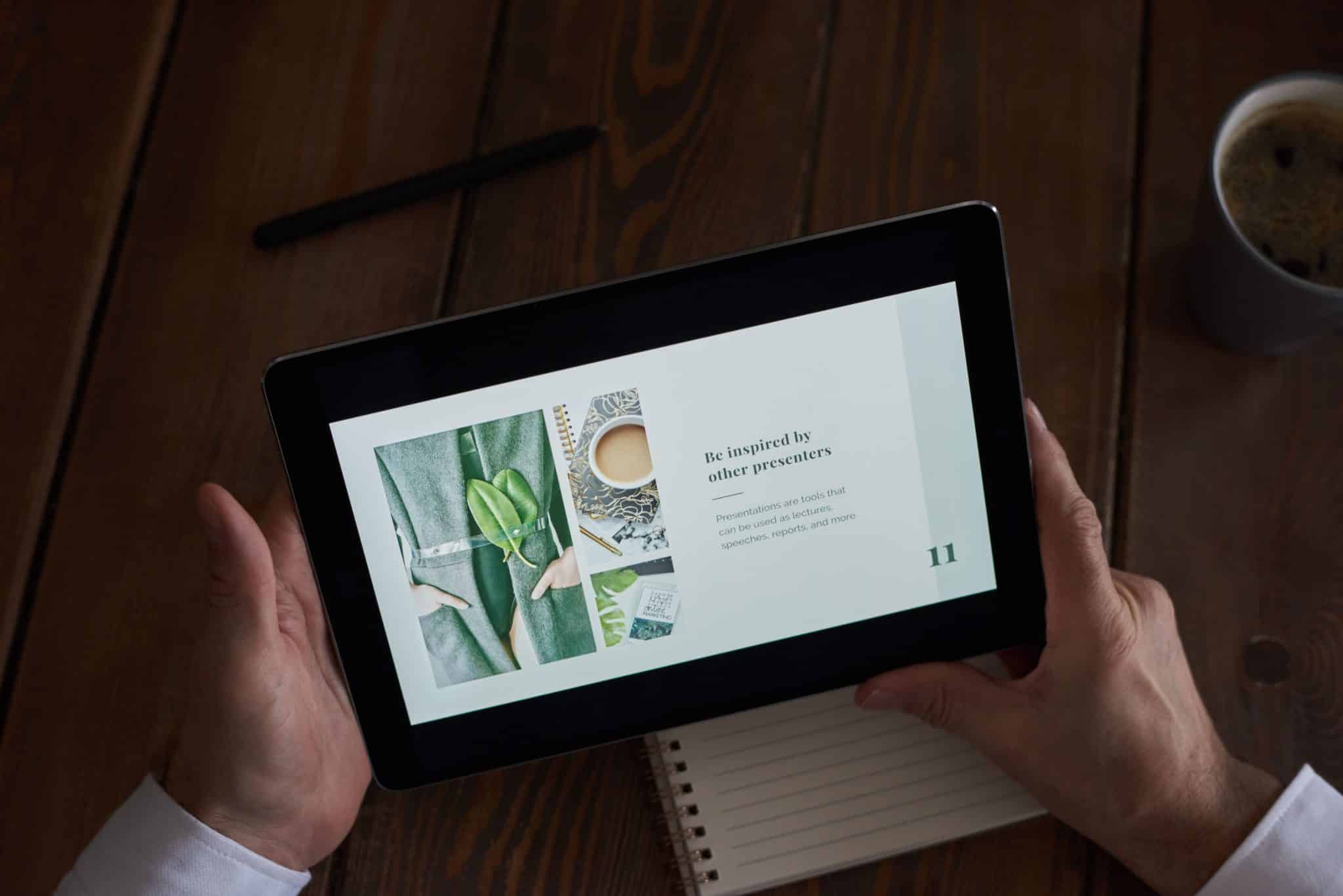 Close-up of hands holding a tablet showing a presentation slide, representing AI presentation makers in 2026