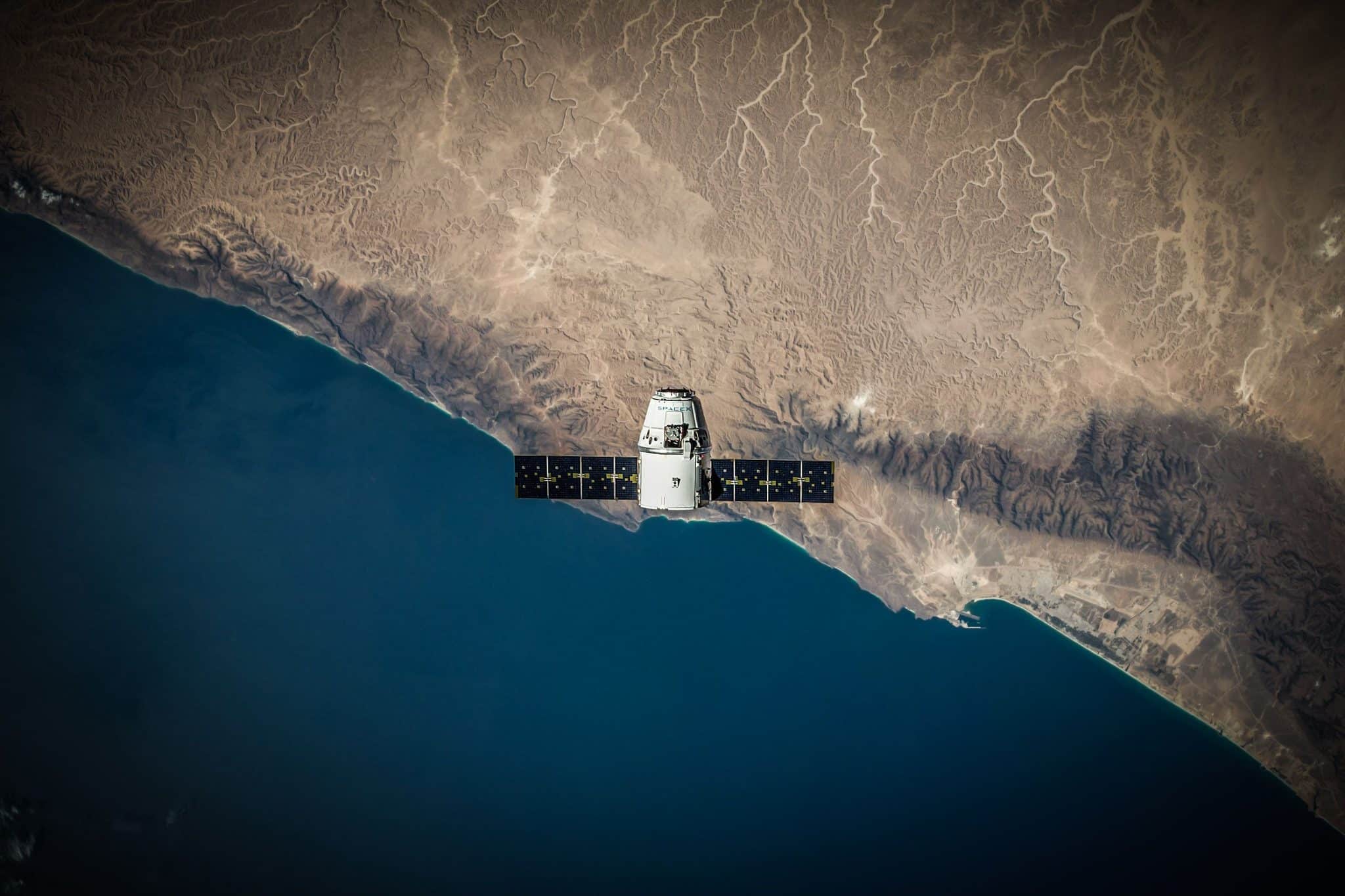 A SpaceX satellite in low Earth orbit above Earth’s coastline, representing the Starmind orbital AI compute project