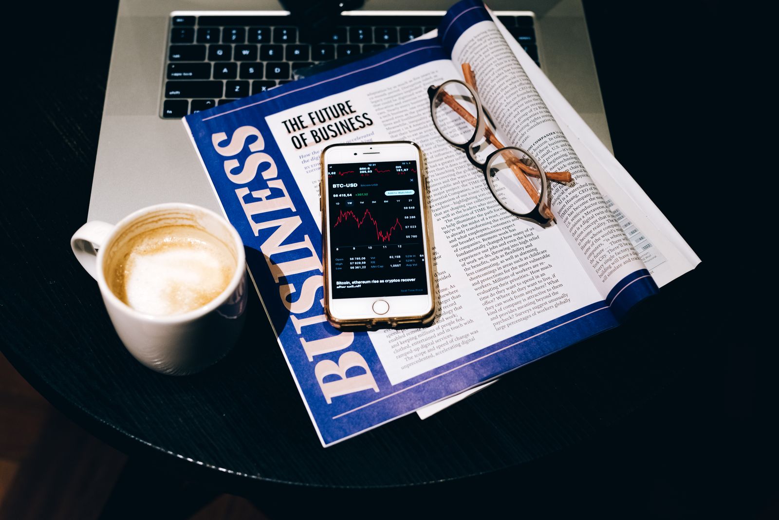Laptop, smartphone, and eyeglasses on a desk representing an AI newsletter reading setup