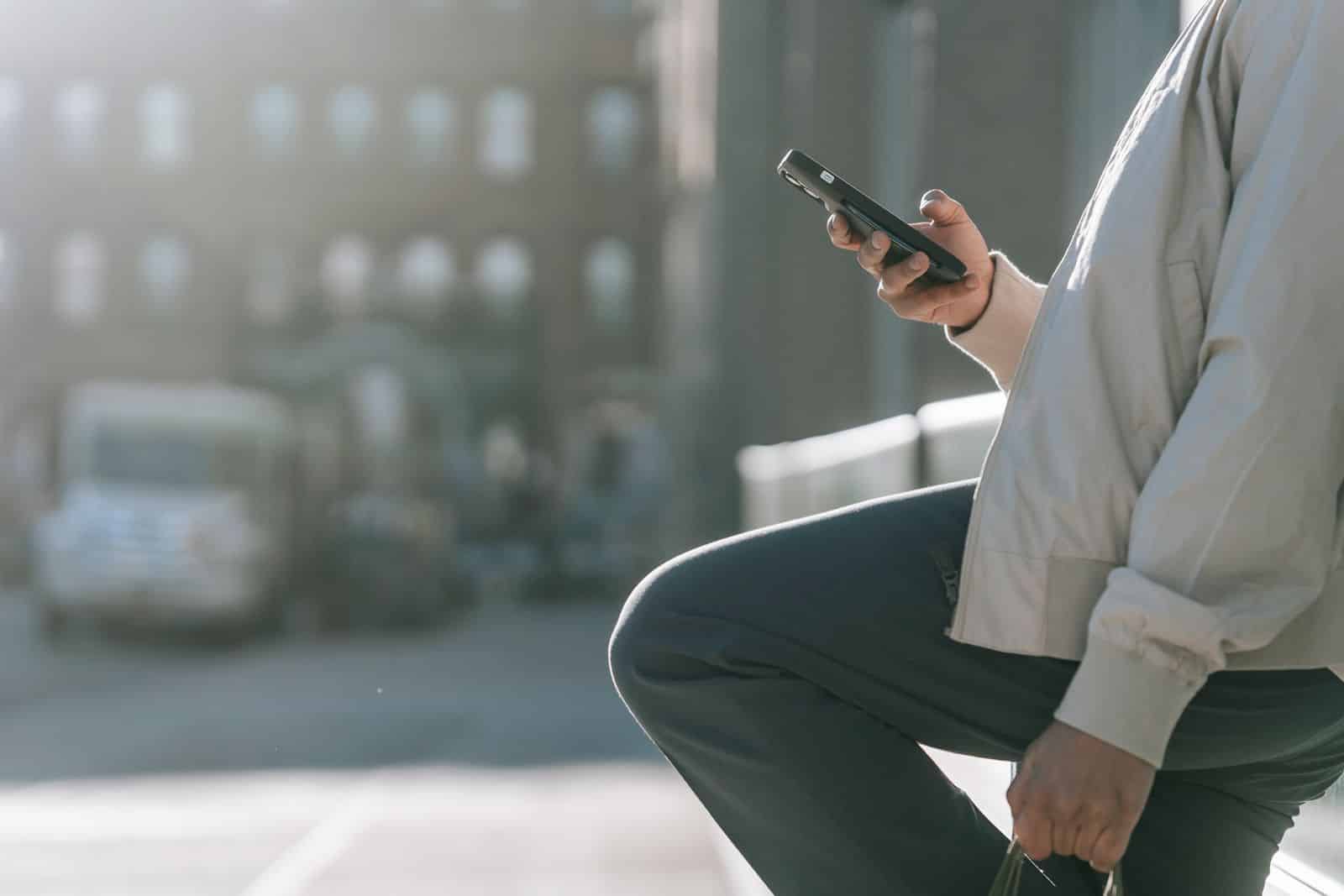 Person using a smartphone outdoors, representing Gemini Auto Browse on mobile