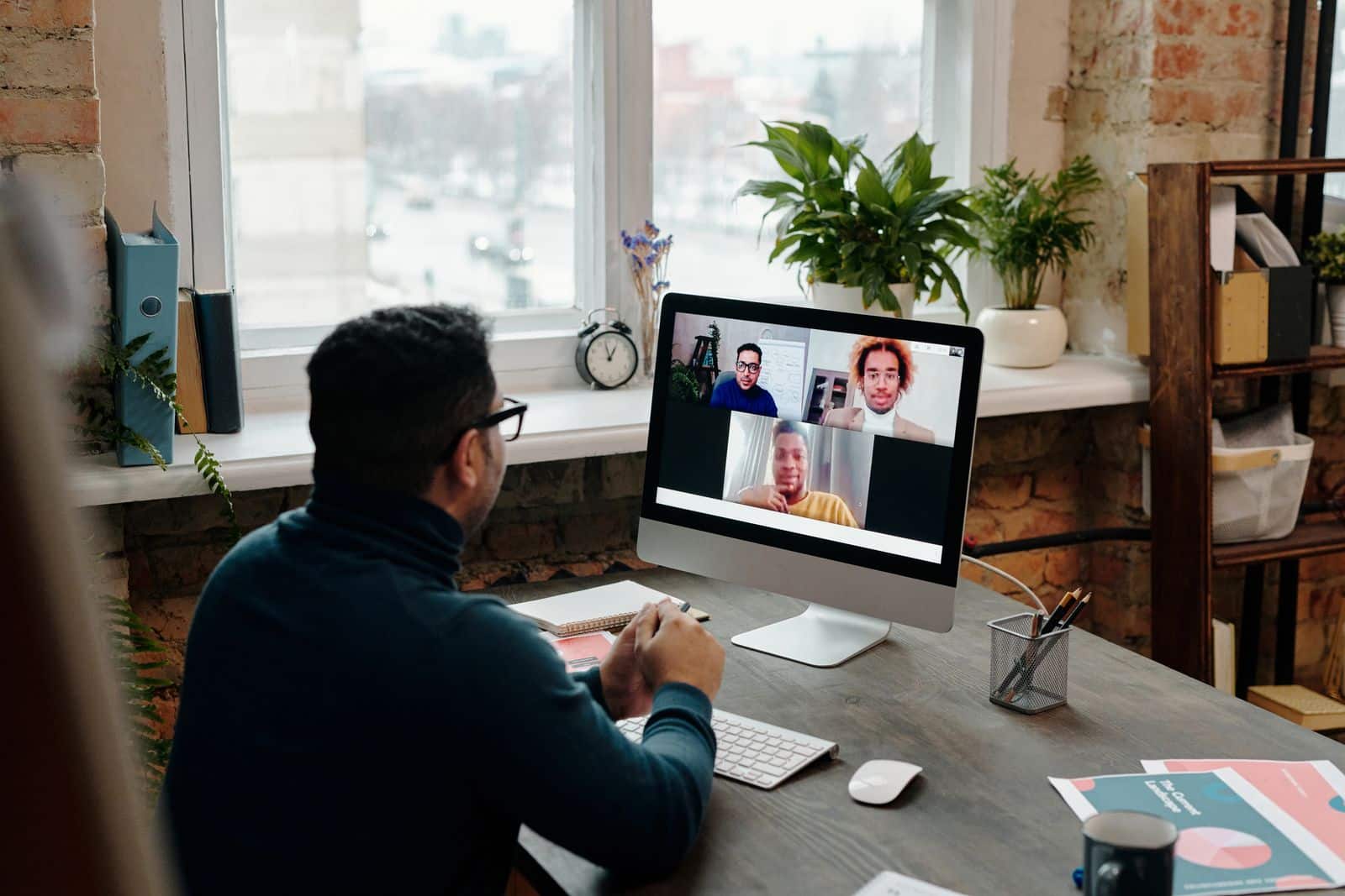 Young woman using earpods for a video call on a laptop indoors, representing Fathom AI notetaker