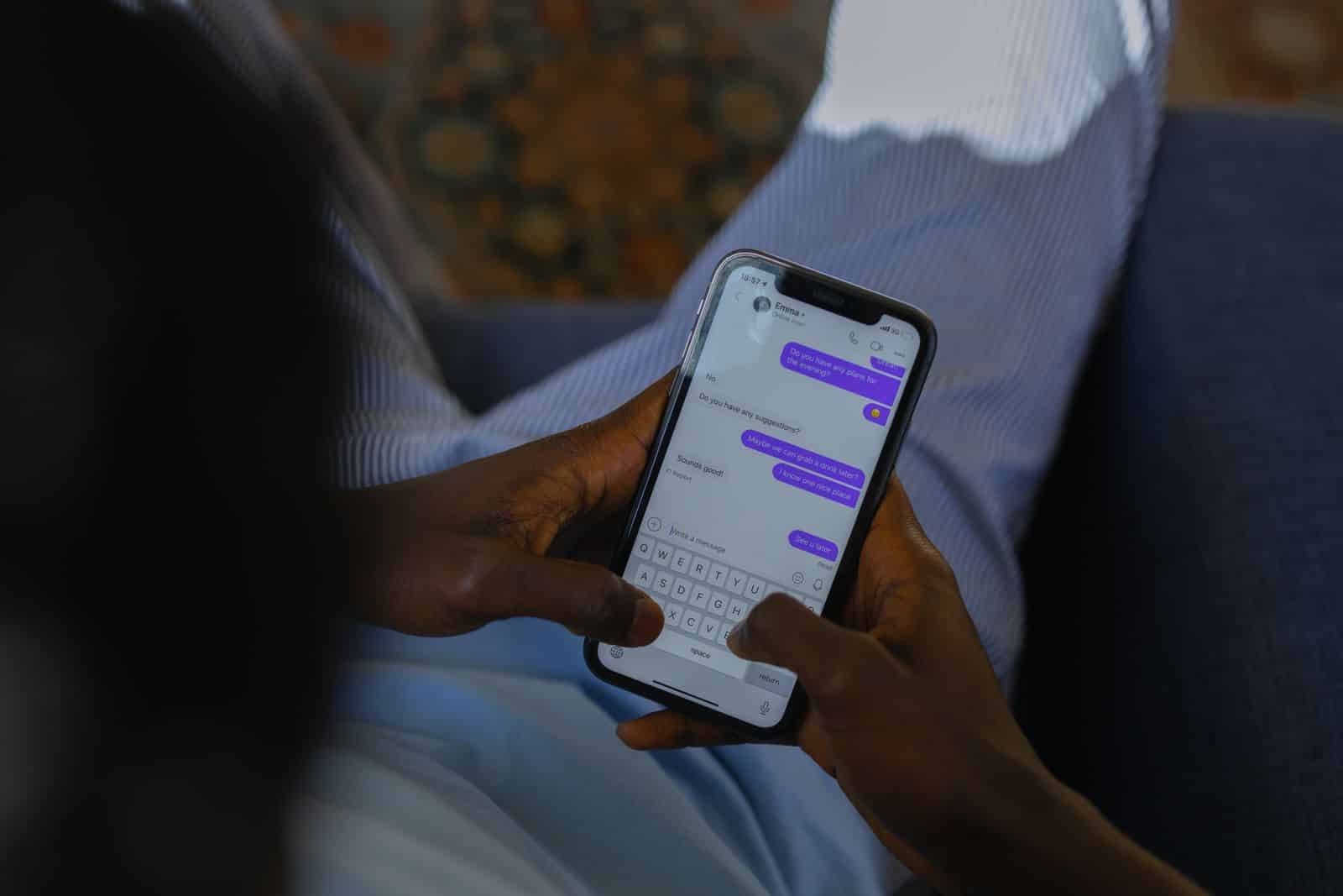 Hands holding a smartphone typing a message, representing GoDaddy Airo AI website builder