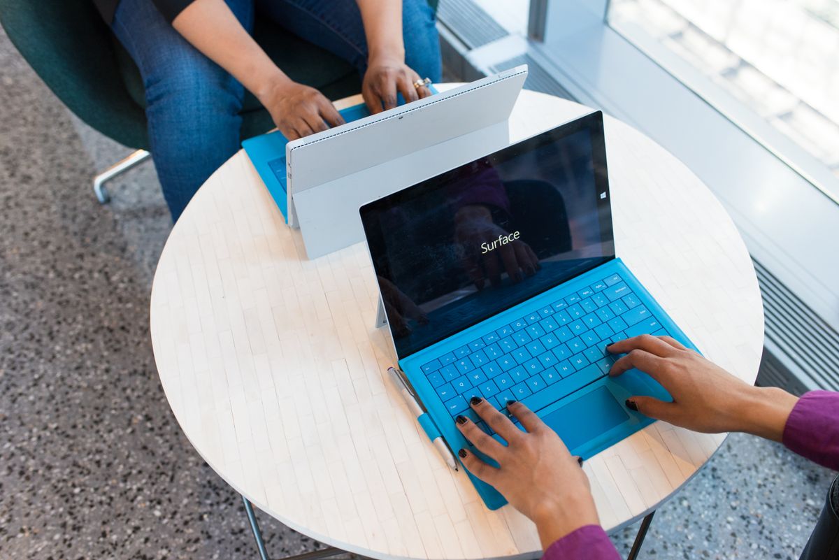 Two people working side by side on laptops, representing a head-to-head comparison of GPT-6 Sol and Claude Opus 5.5