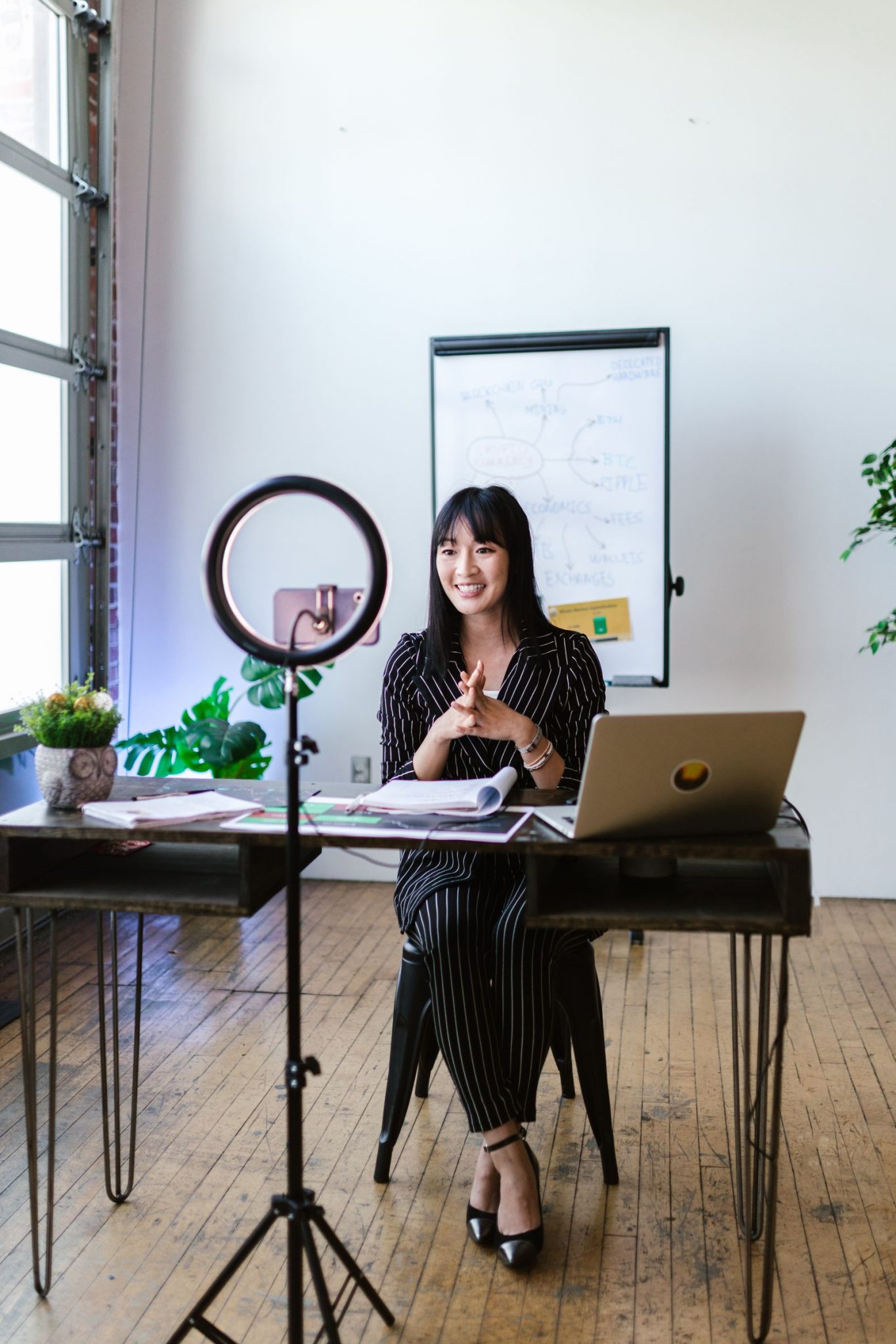 Woman presenting to camera with a ring light in a modern office, representing an AI talking-head avatar video setup
