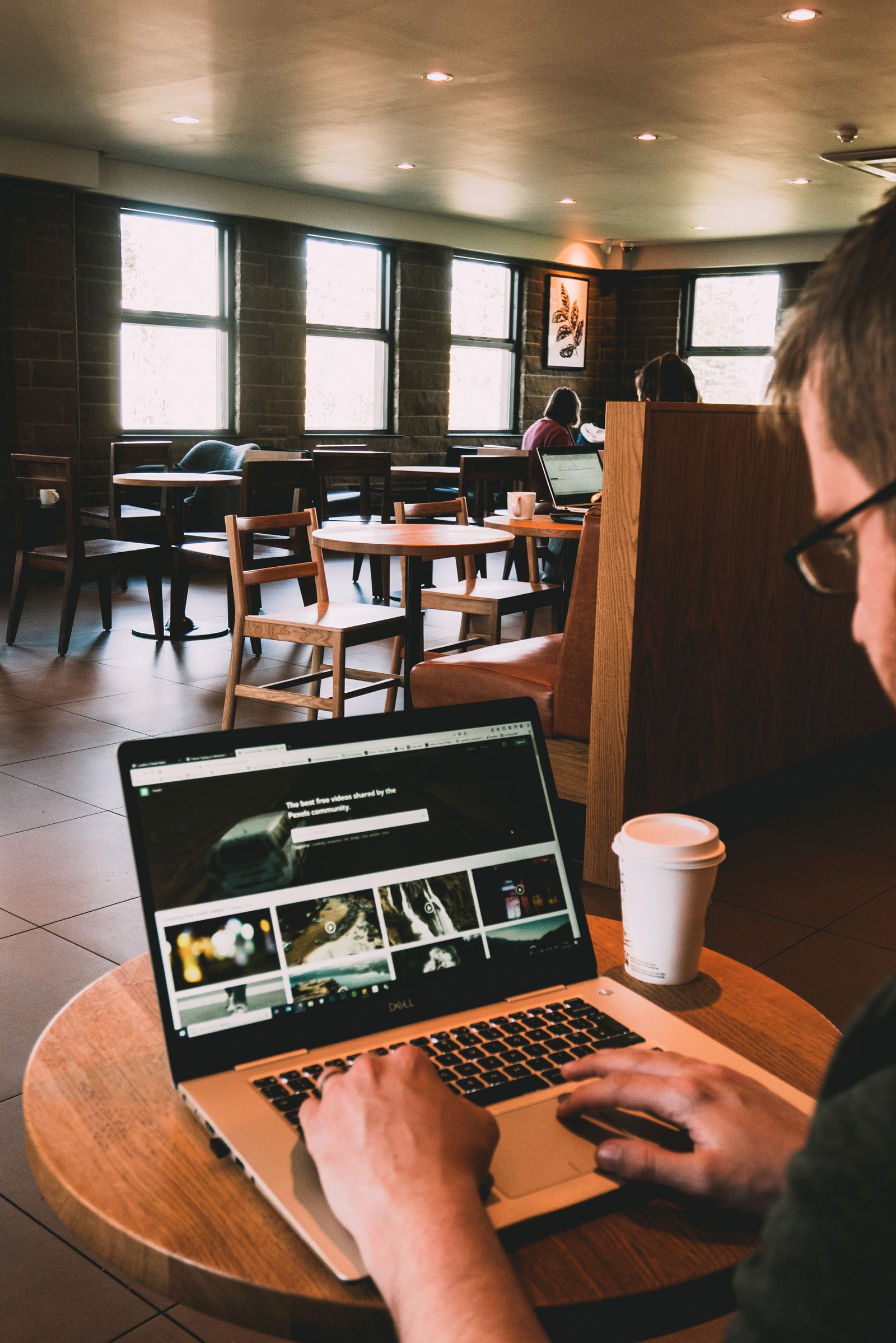 Man using a MacBook on a wooden table, representing Microsoft Edge Copilot Mode