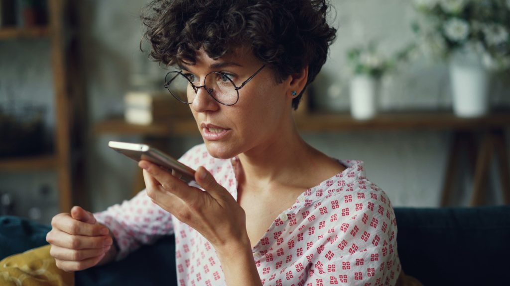 woman using voice command on smartphone at home