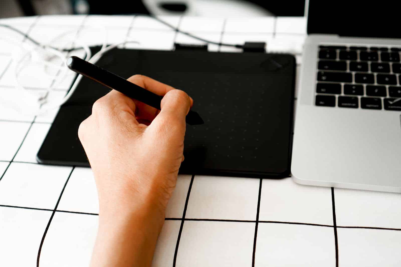 Person using a digital tablet with stylus for design, representing Wix AI website builder